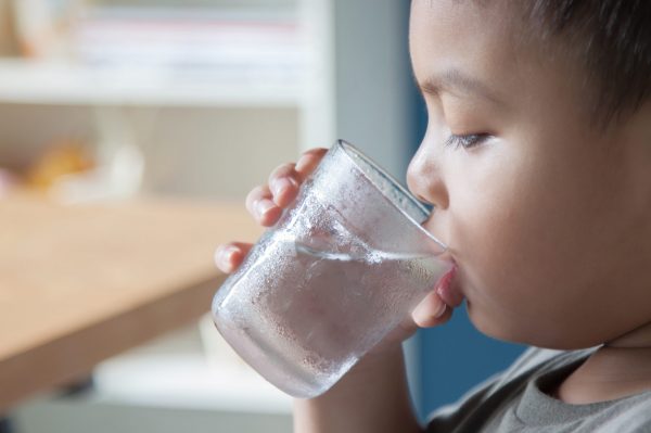 Boy is drinking water in the morning.