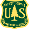 US Forest Service logo, a badge shape outlined in yellow with a dark green background and a yellow fir tree in the center. Text reads US Forest Service Department of Agriculture